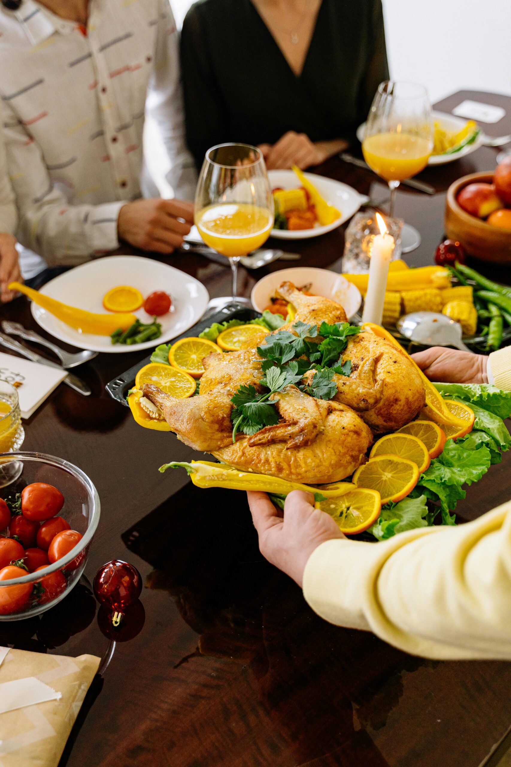 A delicious roasted chicken with lemon slices being served at a festive family dinner table.