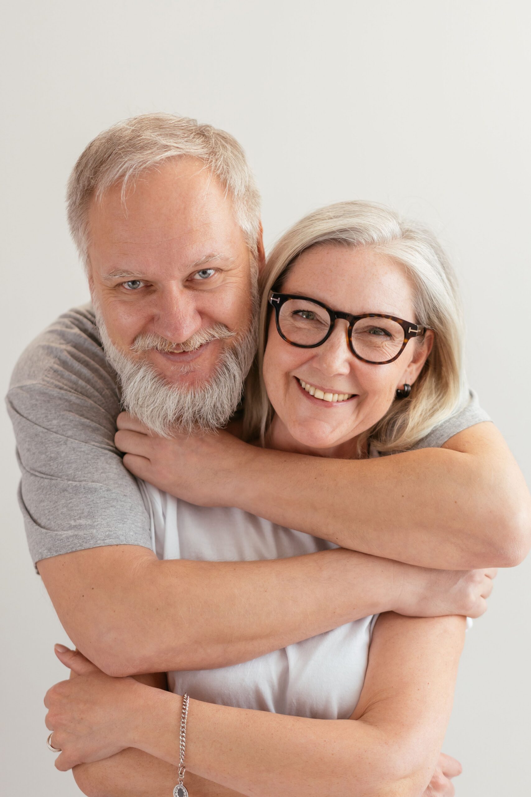 Senior couple embracing and smiling warmly indoors.